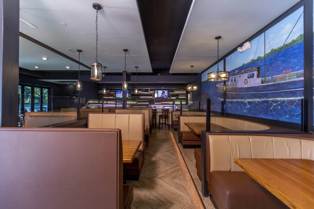 Private dining room at PJ Lobster House in Port Jefferson NY with booth seating, nautical mural, and full bar — available for graduation and communion parties on Long Island